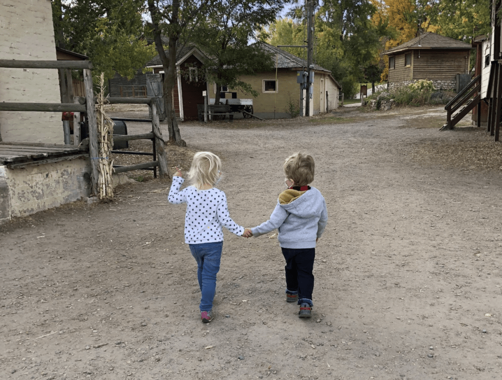 Two toddlers walk together holding hands at Wheeler Farm in Murray, Utah